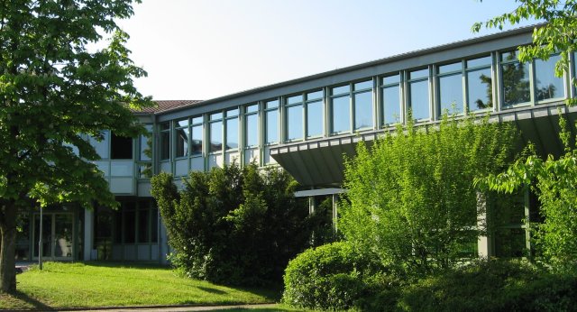 Schulhaus von Außen im Sommer mit viel grün